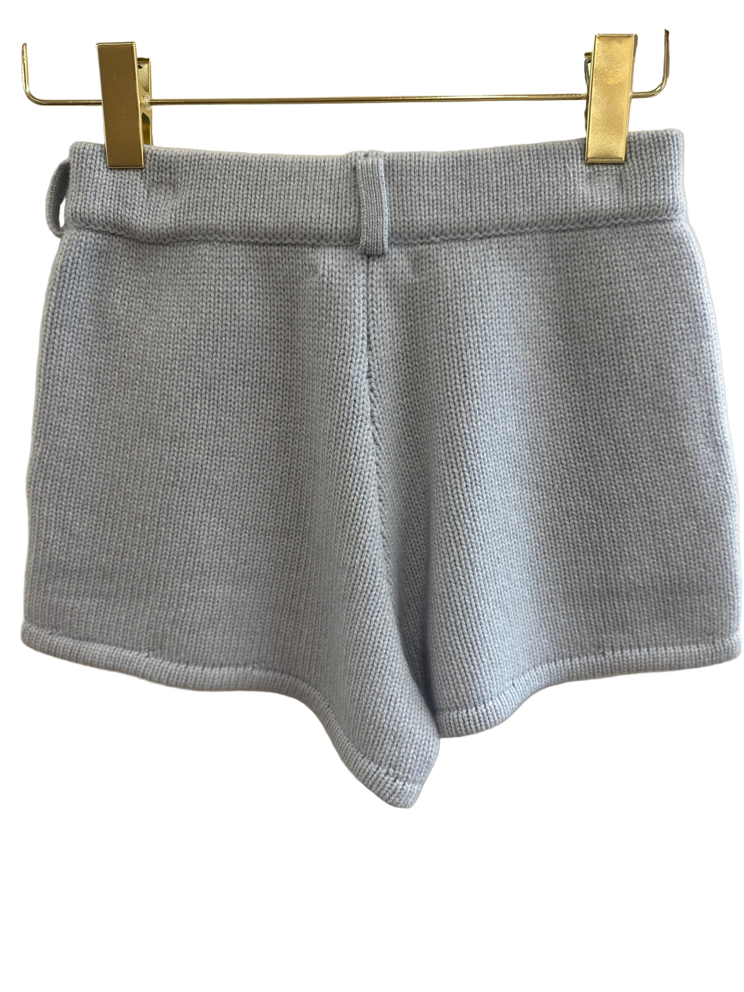 Blue cashmere shorts on a hanger against a white background