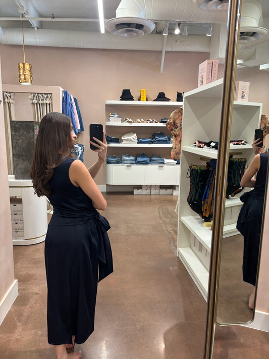 Person wearing a navy blue dress taking a mirror selfie in a store.