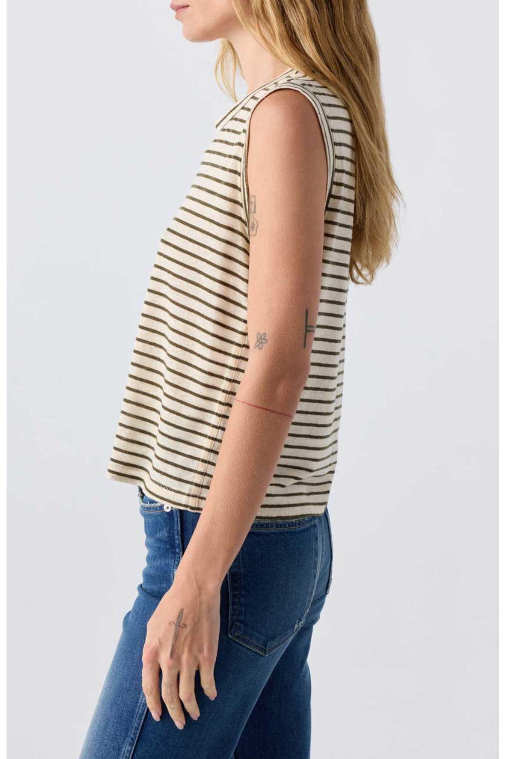 Woman wearing a striped sleeveless top and blue jeans on a white background