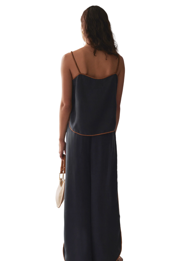 Woman wearing a dark blue slip dress against a marble wall.