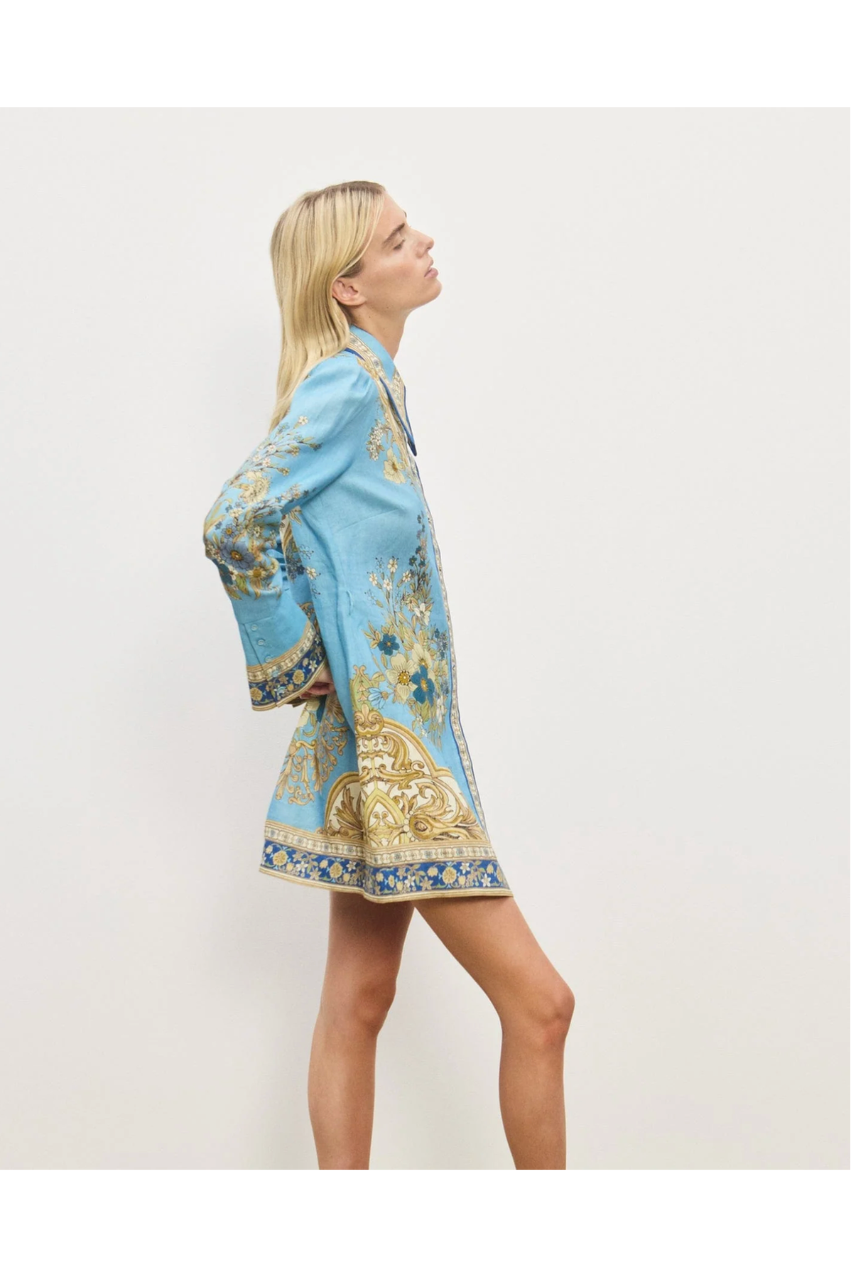 Woman wearing a blue floral dress with gold accents on a white background