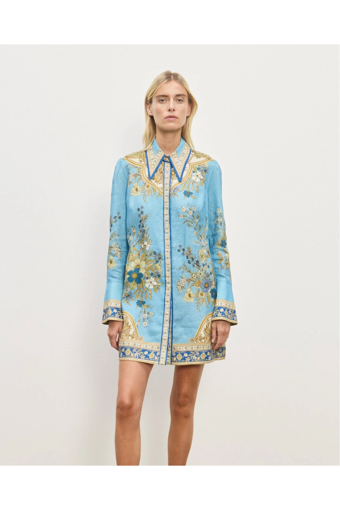 Woman wearing a light blue dress with floral embroidery on a white background