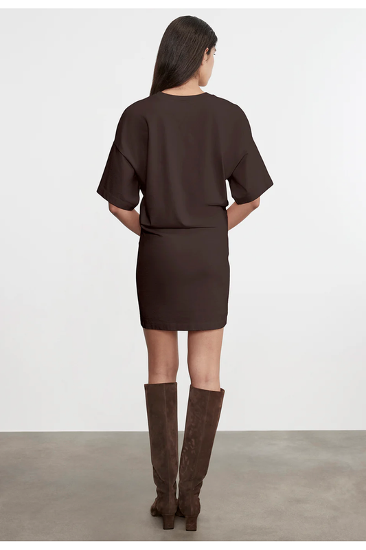 Woman wearing a brown outfit with knee-high boots on a plain background