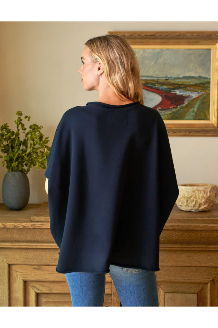 Person wearing a navy sweater in a room with a painting and decorative items.
