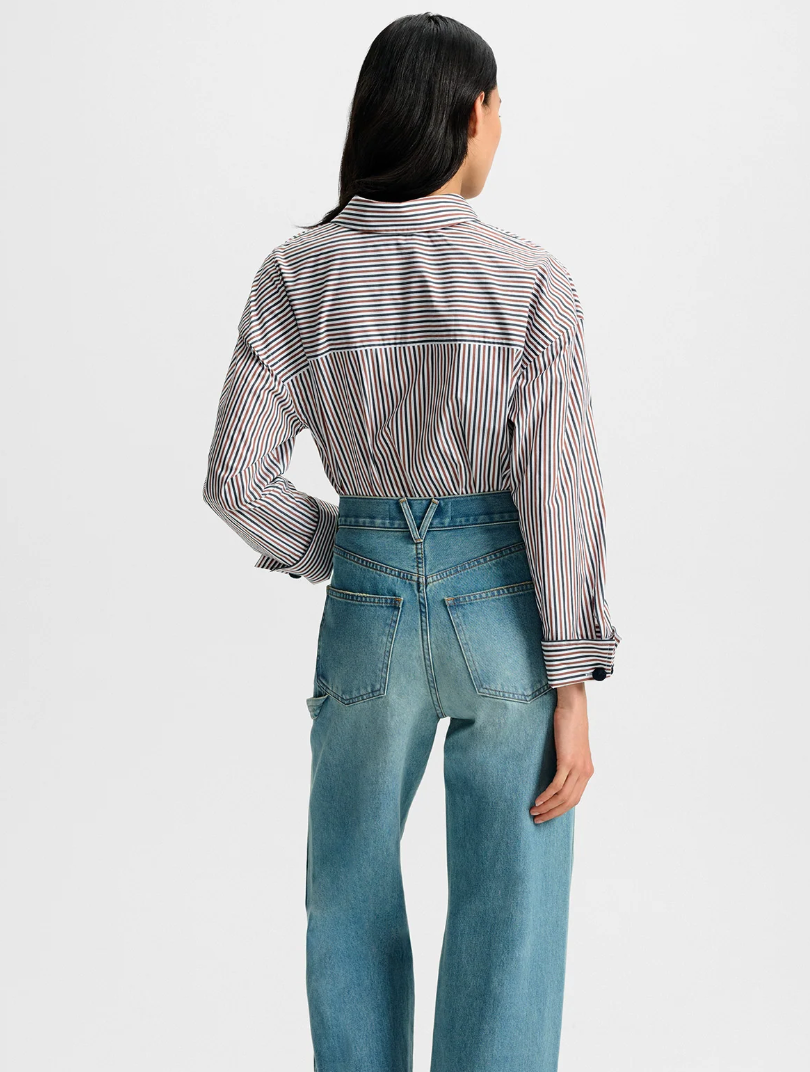 Person wearing a striped shirt and blue jeans on a white background