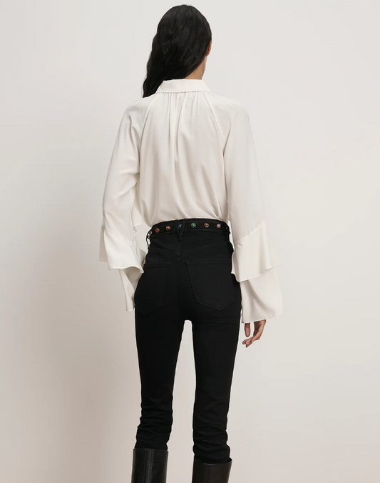 Person wearing a white shirt and black pants on a plain background