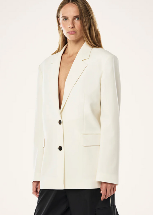 Woman wearing a white blazer over a black top on a white background
