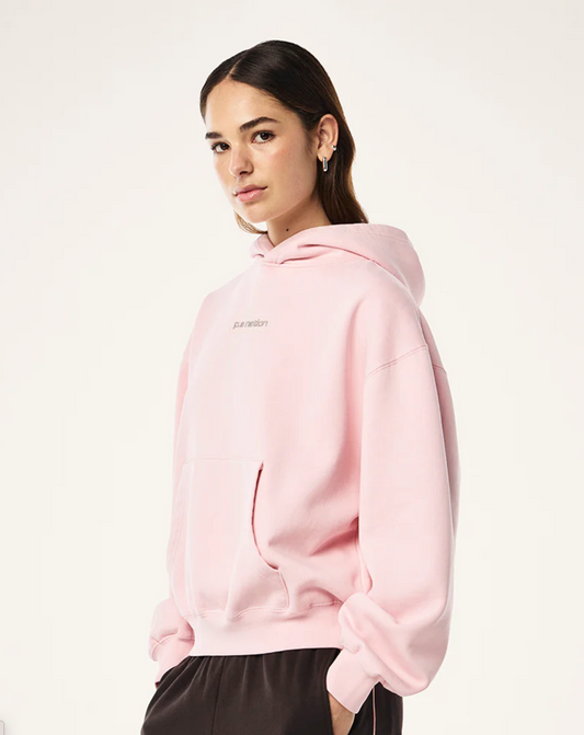 Person wearing a pink hoodie with a brand logo on a white background