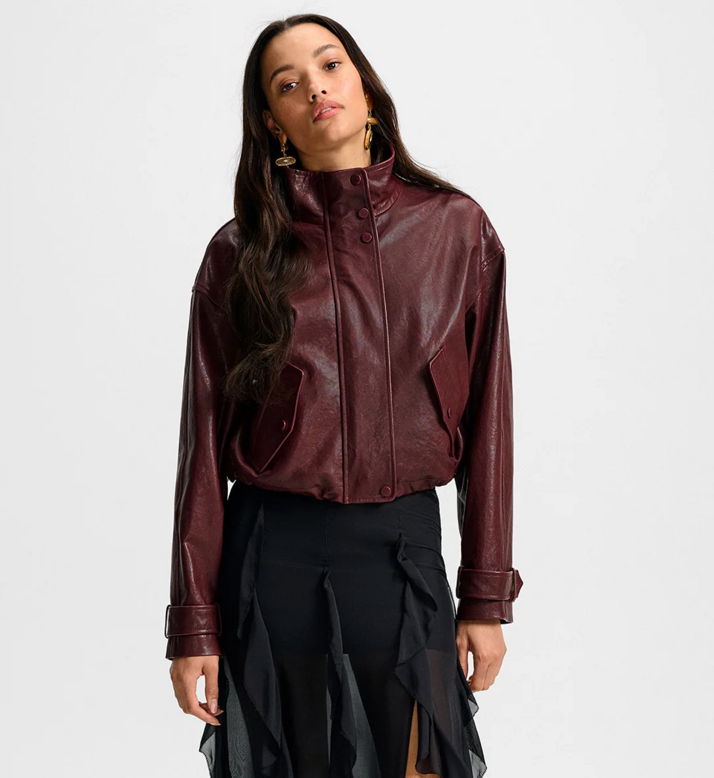 Woman wearing a burgundy leather jacket on a white background