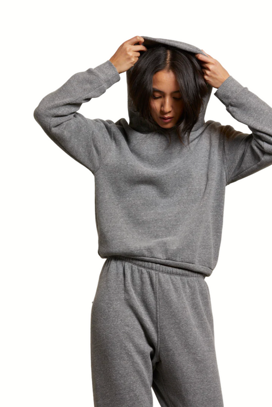 Person wearing a gray sweatshirt and pants against a plain background