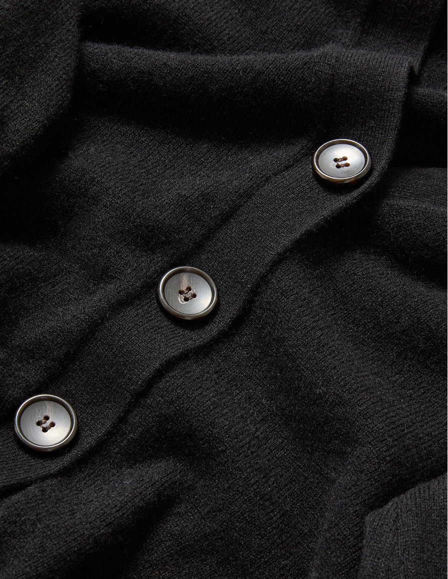 Close-up of a black garment with buttons on a dark background