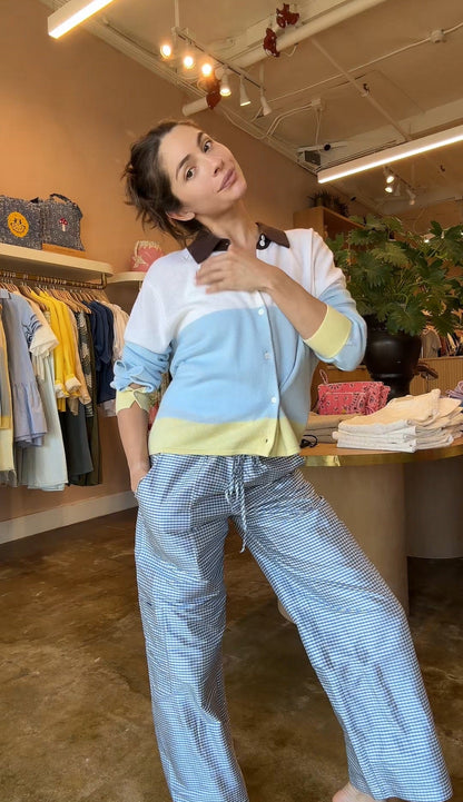 Woman in a light blue and white outfit standing in a clothing store.