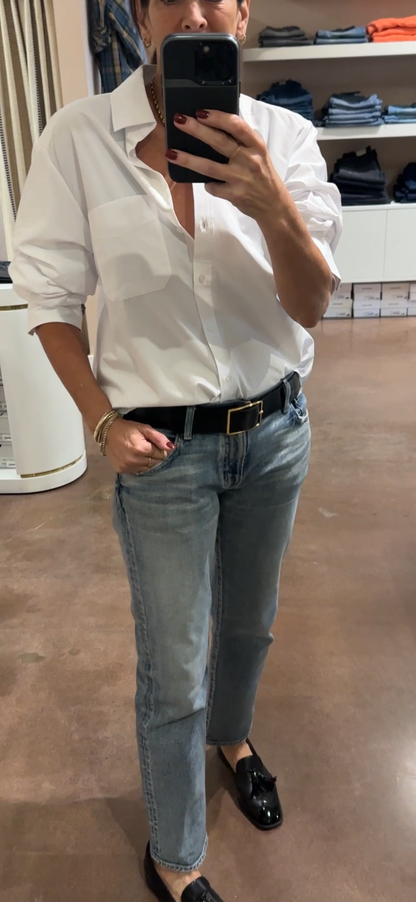 Person wearing a white shirt and blue jeans taking a mirror selfie.
