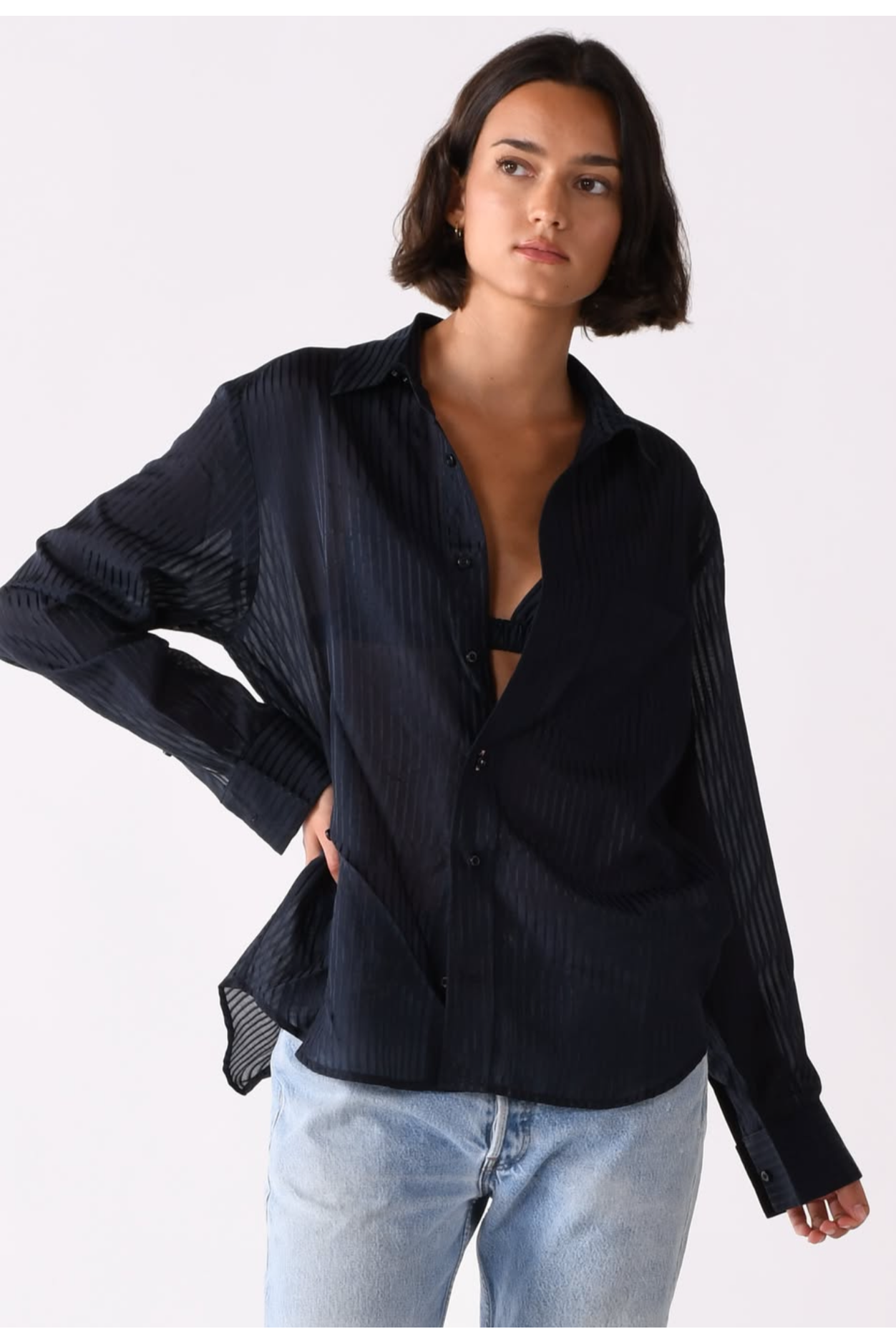 Woman wearing a black shirt and light blue jeans on a white background