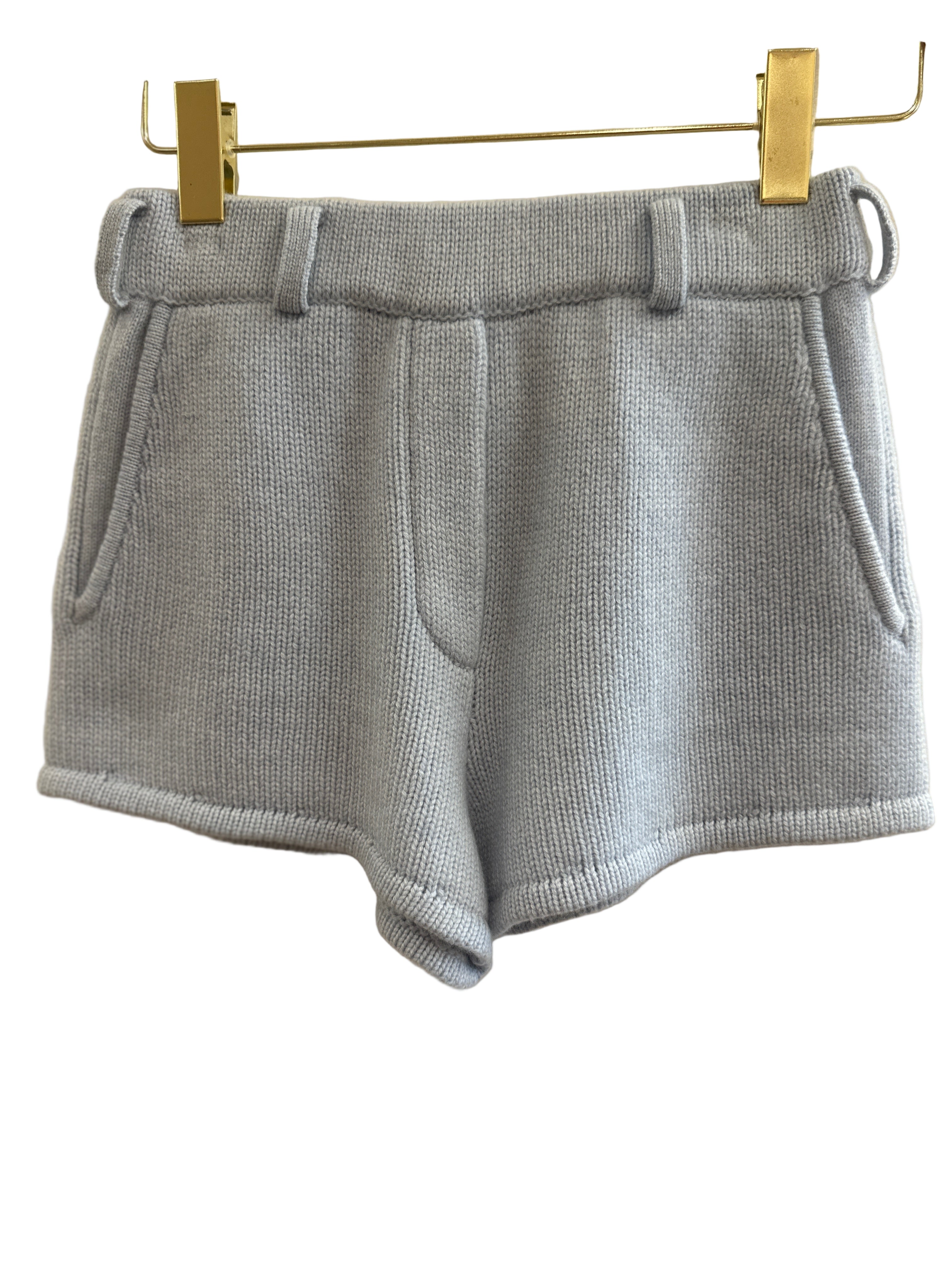 Blue cashmere shorts with pockets on a hanger against a white background