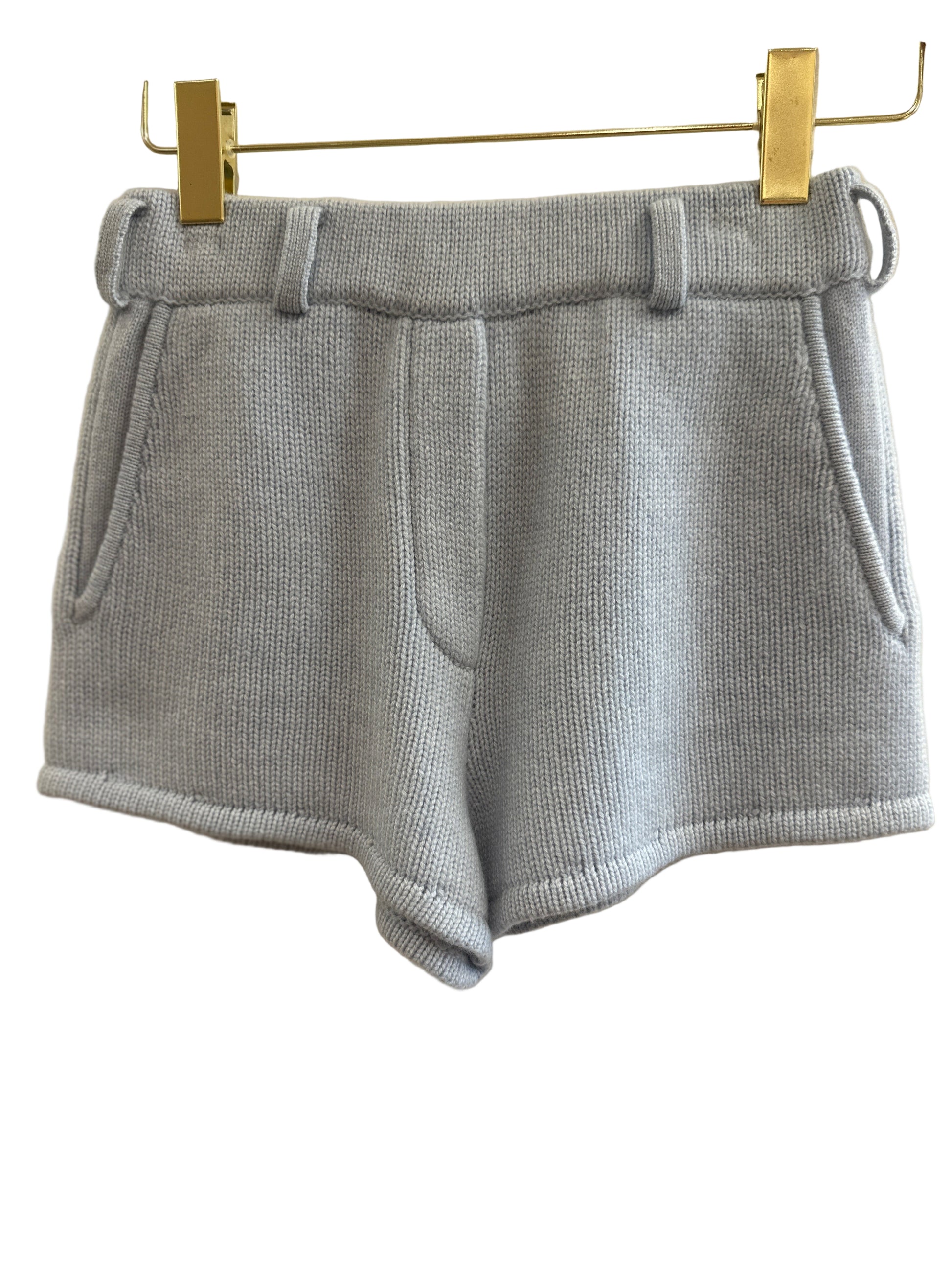 Blue cashmere shorts with pockets on a hanger against a white background