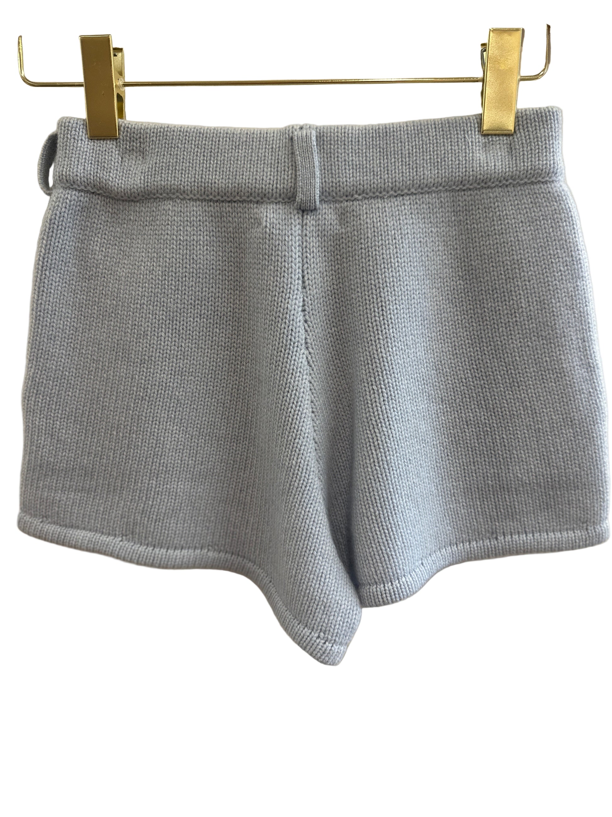 Blue cashmere shorts on a hanger against a white background