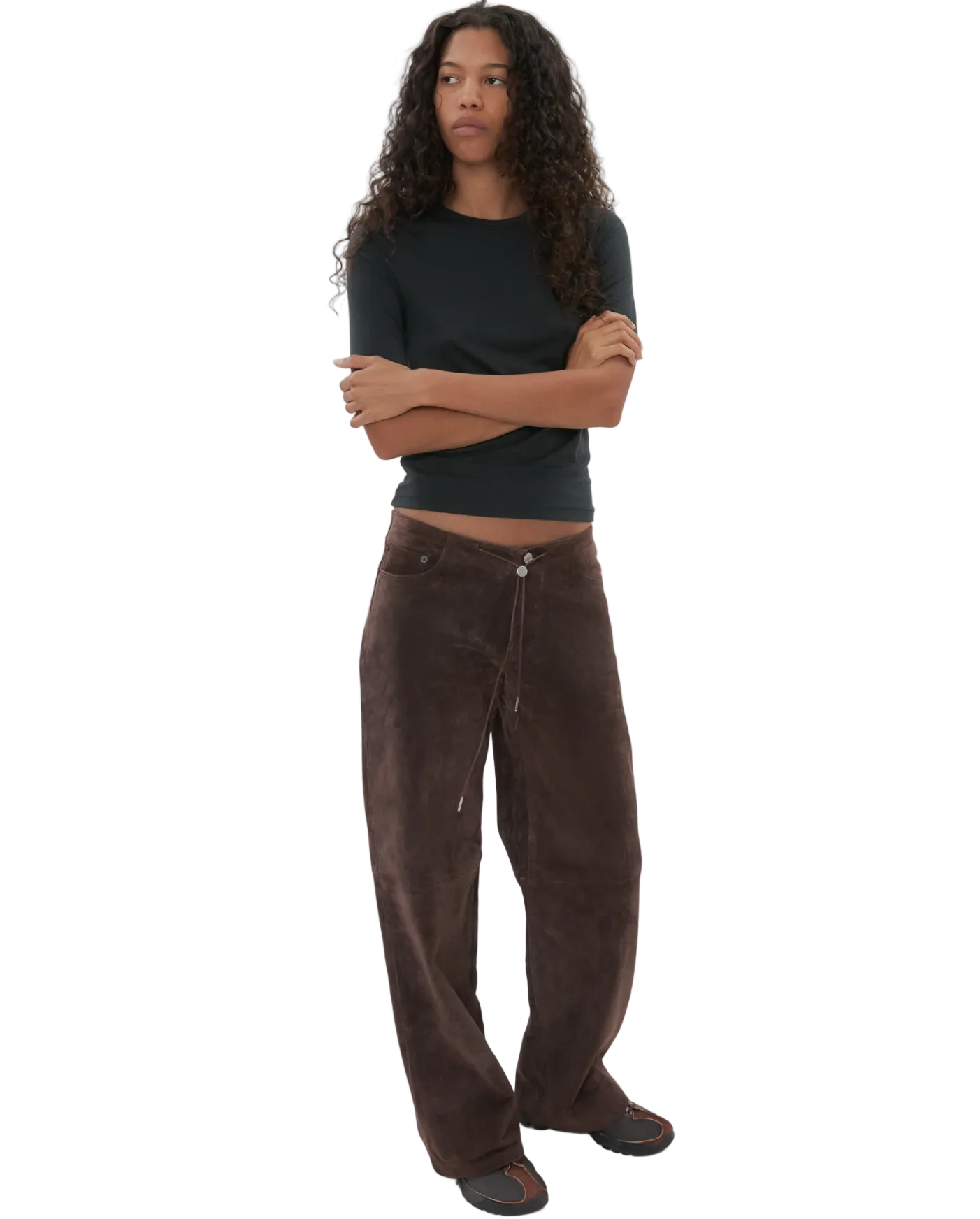 Person wearing a black top and brown pants on a white background