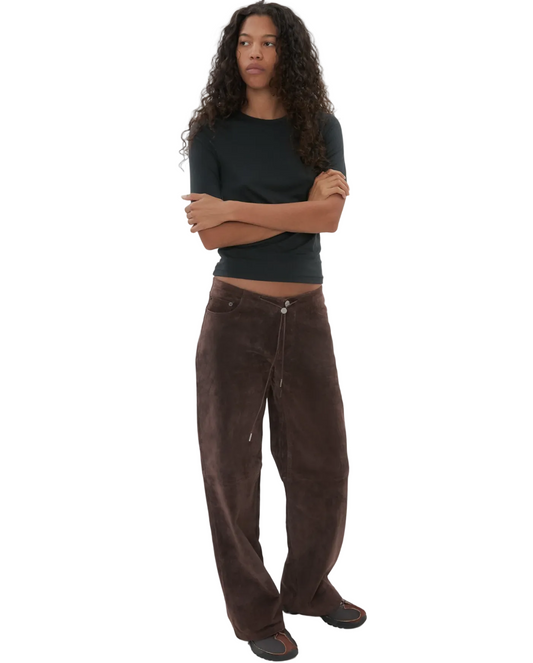 Person wearing a black top and brown pants on a white background