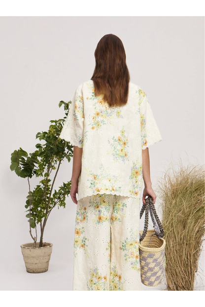 Woman wearing a floral outfit holding a basket, standing next to plants on a white background