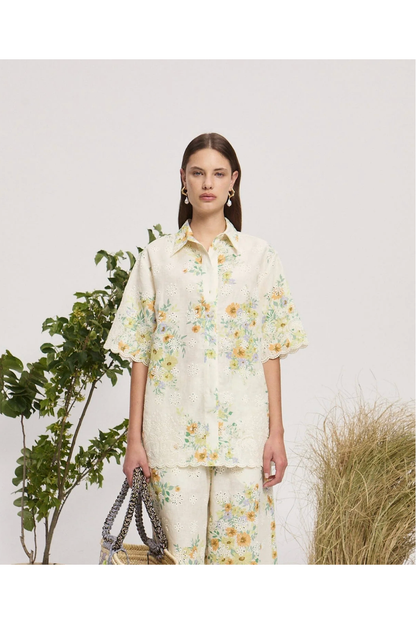 Woman wearing a floral outfit with a white background and plants.