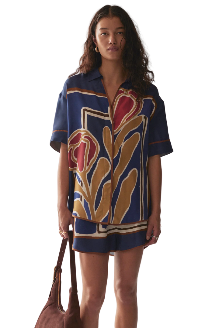 Woman wearing a patterned shirt and shorts set with a marble background