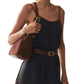 Woman wearing a navy shorts with a brown belt and carrying a brown handbag on a white background