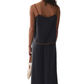 Woman wearing a dark blue slip dress against a marble wall.