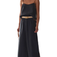 Woman wearing a black slip dress with a beige belt on a marble background