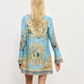 Woman wearing a blue dress with gold and white floral patterns on a white background