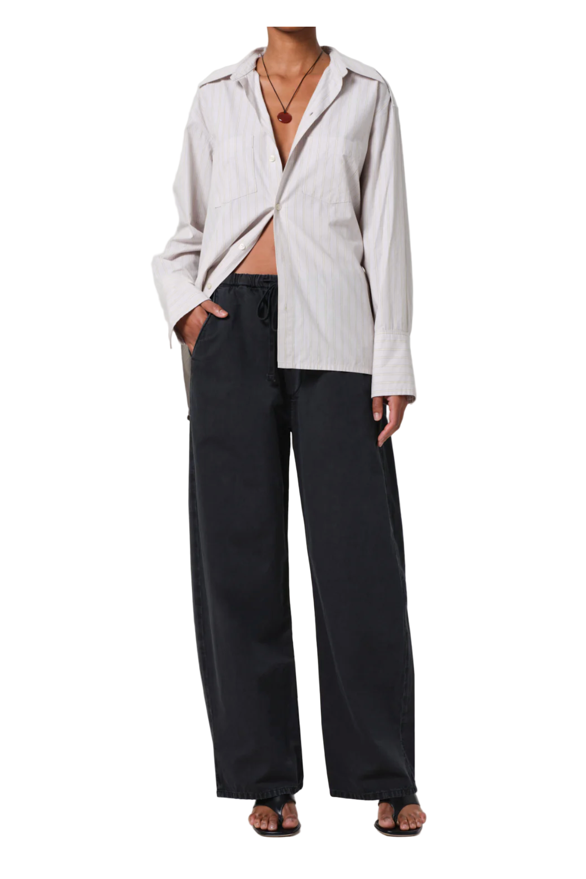 Person wearing a light-colored jacket and black pants on a white background