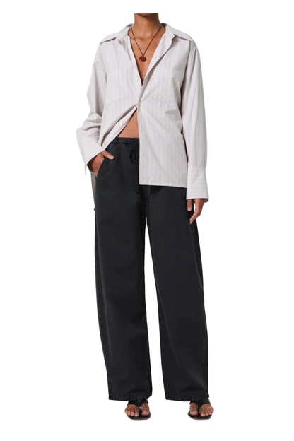 Person wearing a light-colored jacket and black pants on a white background