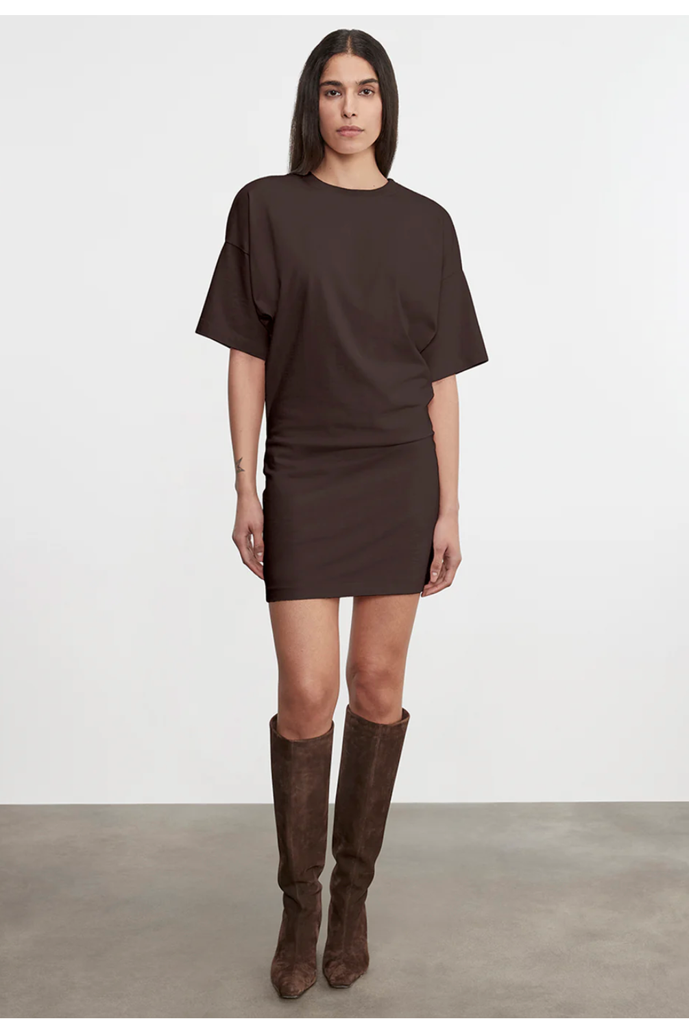 Woman wearing a brown dress and knee-high boots on a white background