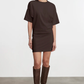 Woman wearing a brown dress and knee-high boots on a white background