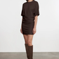 Woman wearing a brown dress and knee-high boots against a white background