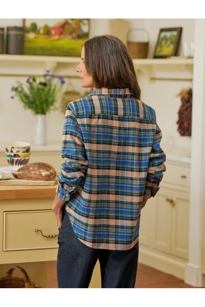 Person wearing a blue and beige plaid shirt in a kitchen setting