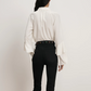 Person wearing a white shirt and black pants on a plain background