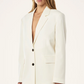Woman wearing a white blazer over a black top on a white background