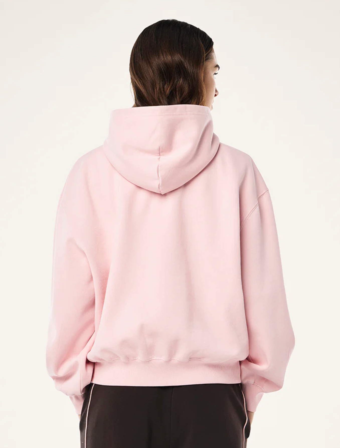Person wearing a pink hoodie from behind on a white background