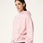 Person wearing a pink hoodie with a brand logo on a white background