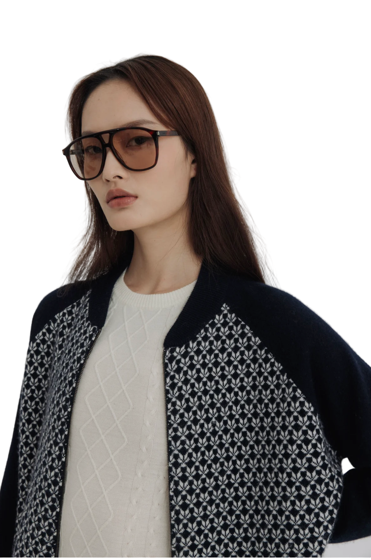 Woman wearing a patterned cardigan over a white sweater on a plain background