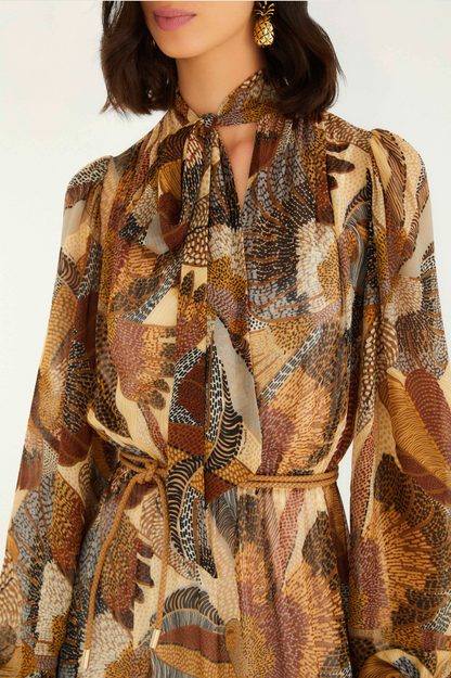 Woman wearing a patterned dress with a scarf around her neck against a white background
