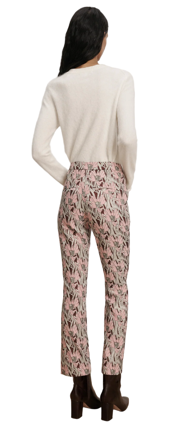 Person wearing a white sweater and patterned pants on a plain background