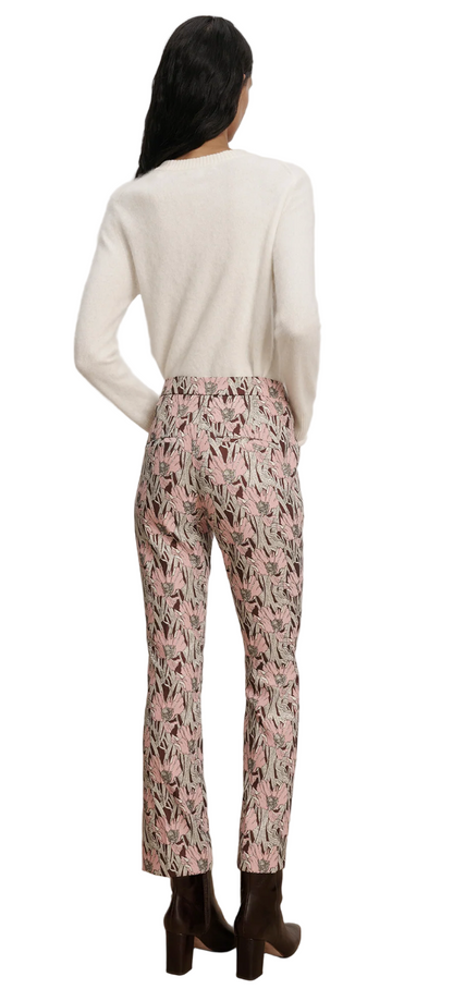 Person wearing a white sweater and patterned pants on a plain background