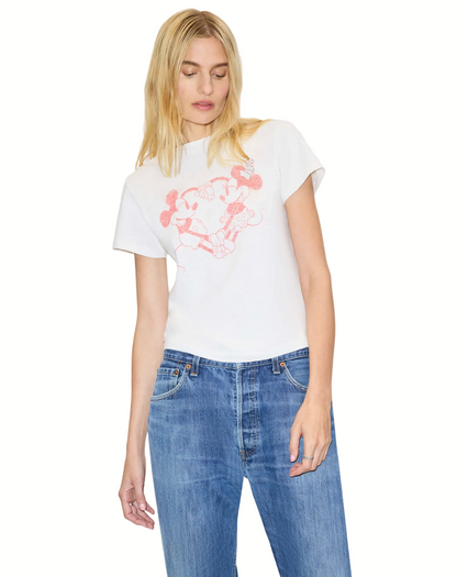 Woman wearing a white t-shirt with a graphic design and blue jeans on a plain background