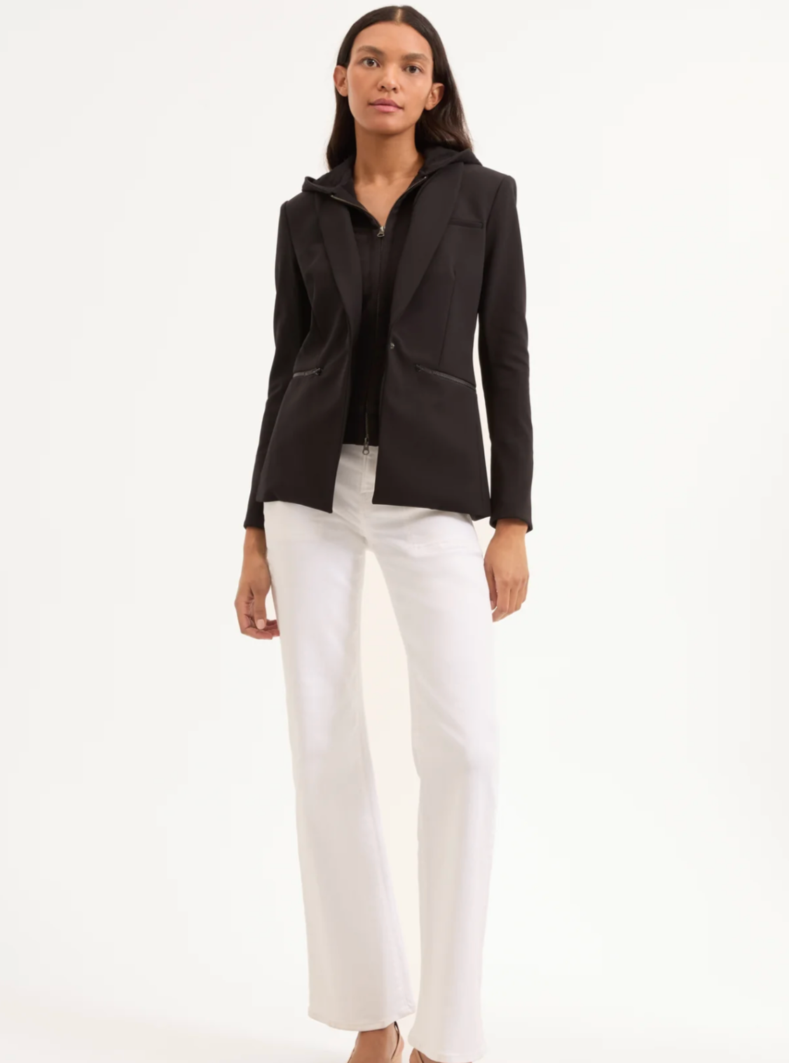 Woman wearing a black blazer and white pants on a white background