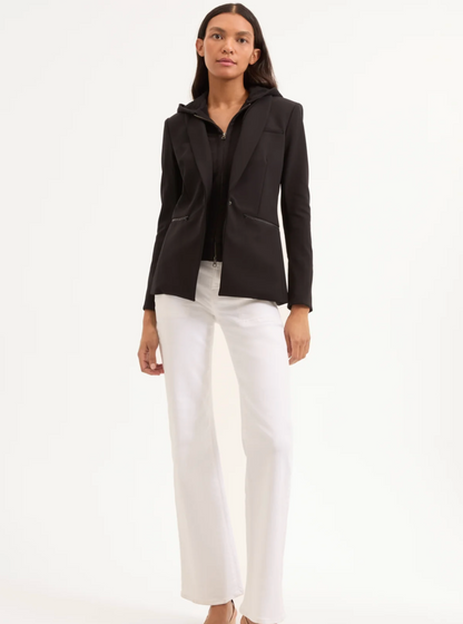 Woman wearing a black blazer and white pants on a white background