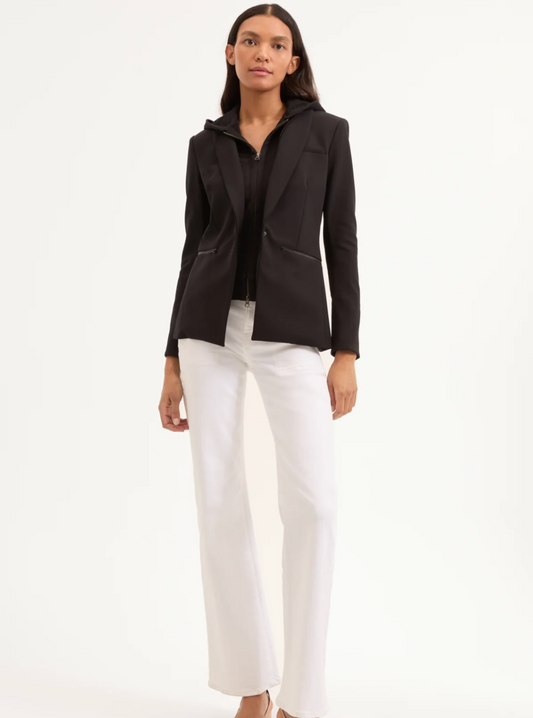 Woman wearing a black blazer and white pants on a white background