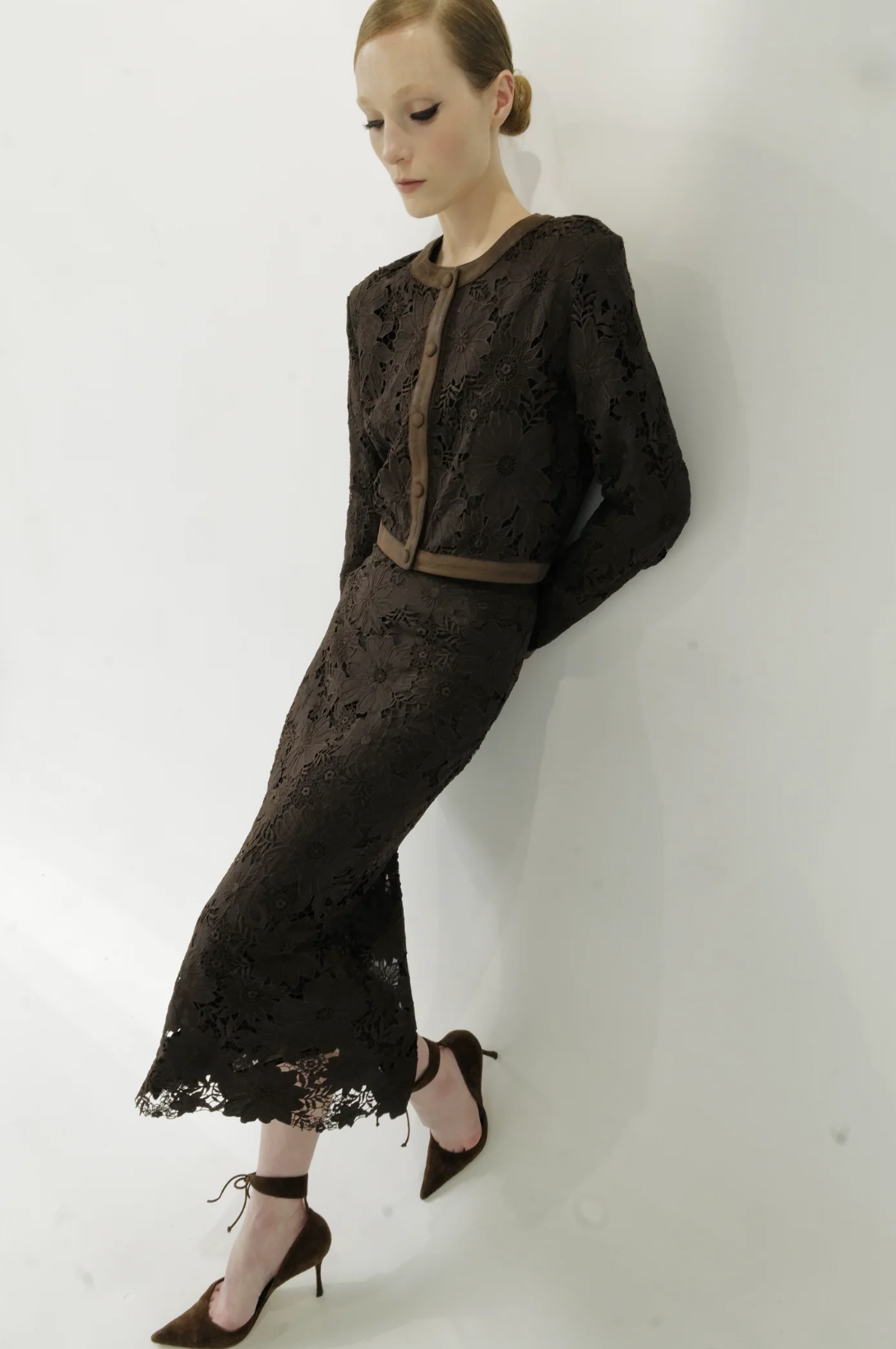 Woman wearing a black lace outfit against a white background