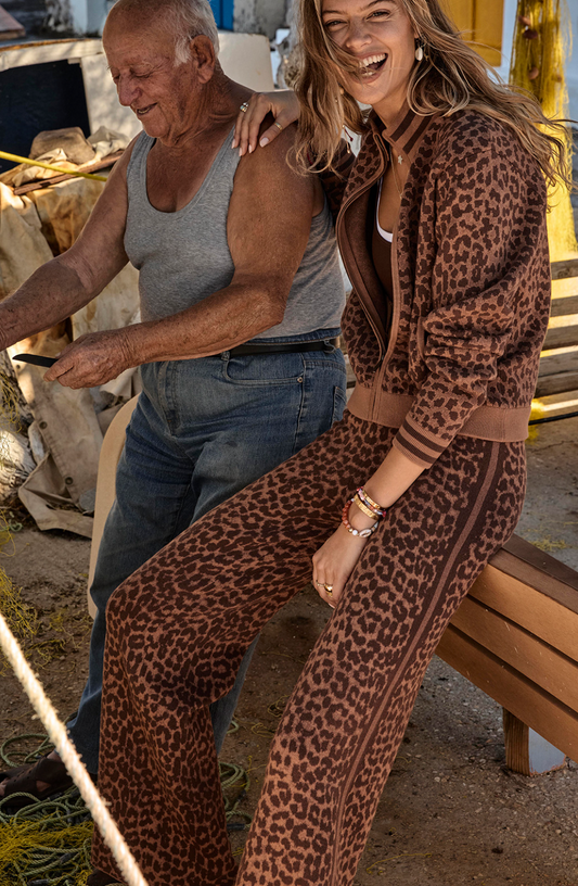 Two people, one in a leopard print outfit and the other in casual clothing, sitting together outdoors.